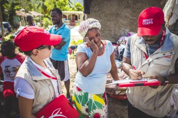 Mercy corps employees interview someone and fill out paperwork.