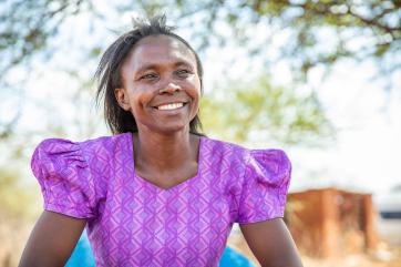 Kenyan woman smiling and looking past the camera.