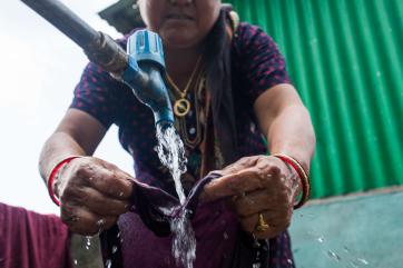 A person using a water spigot.