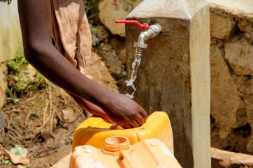 Hands collecting water at water station.
