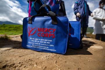 A mercy corps urgent supplies bag which includes items like face masks and shields, hand sanitizer, thermometers, soap, and oximeters.