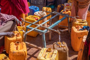 February 2022, baidoa, somalia. families fill jerry cans at a water point built by mercy corps at the loojele idp camp near baidoa.