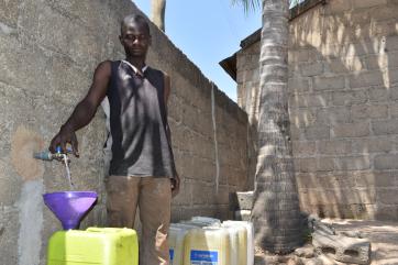 Muktar fetching water from the tap to mix the dough.