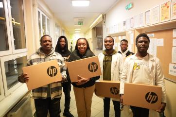 Students holding boxes with new computer equipment.