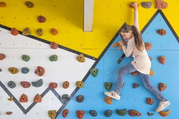 A young person traversing a climbing wall.