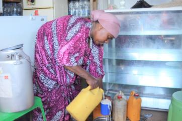 Ethiopian woman bending over pouring milk