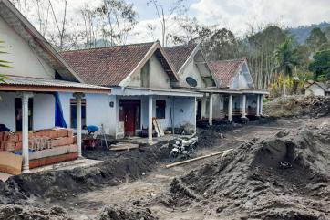 Houses in a village damaged after a nearby volcano erupted.