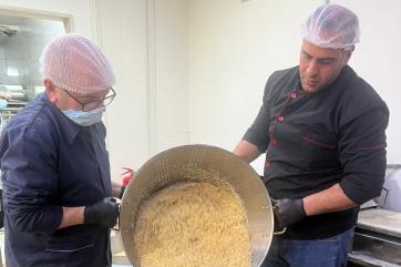 Two lebanese men preparing a large pot of food.