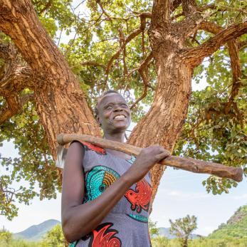 A person takes a break from weeding their crops on their land in Uganda.