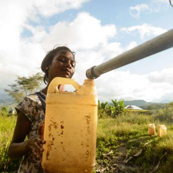 A person in timor leste filling up a jerrycan with water from a pipe.