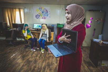 A woman showing a laptop computer to a group