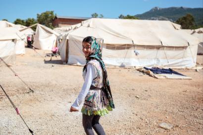 Girl in a refugee camp in greece walking away looking at the camera