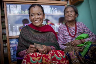 Two women sitting in a store front and smiling.