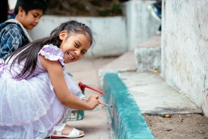 Neighborhood children paint a colorful mural on the front of a youth center.