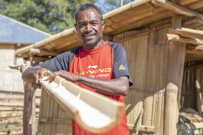 A farmer stands next to their bamboo rainwater collection system.