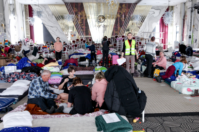 Families rest on mattresses on the floor of a reception center for refugees fleeing ukraine.