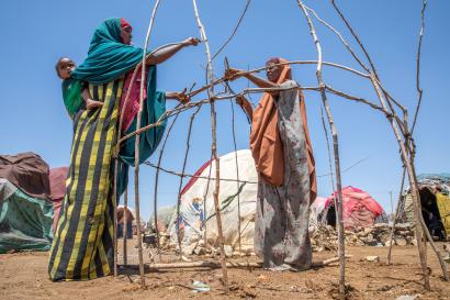 Two sisters building a temporary shelter out of sticks and ragged cloth after arriving at an idp camp outside baidoa.