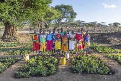 Kenyan community members standing as a group amidst agricultural crops.