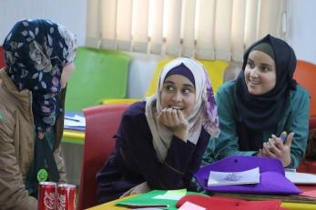 Three girls wearing headscarves talking to one another and smiling