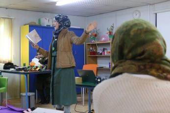 A woman presenting and reading from a book