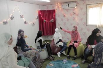 A group of girls laughing and chatting in a decorated youth space, sitting on bean bag chairs