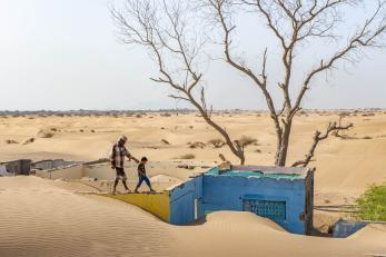 Man and boy walking on rooftop surrounded by sand