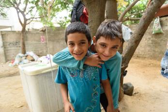 Two young boys, both wearing blue shirts, smiling