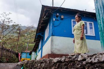 Woman in green and white dress next to row of small buildings