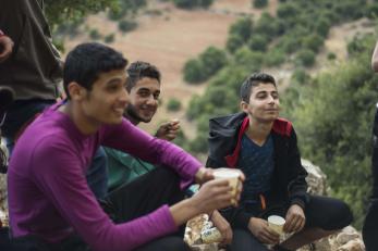 Three young men holding cups and sitting