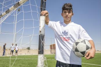 Islam in a mercy corps soccer jersey standing by the soccer net