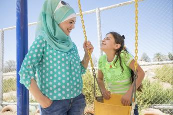 Hilda smiles at her daughter, renad, as renad leans on a swing