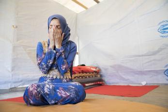 Iman is pictured seated on the floor with her hands raised to cover her face