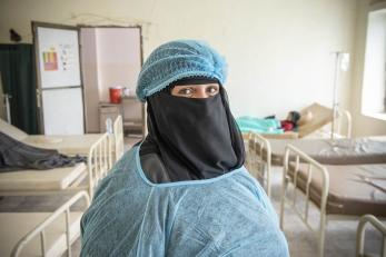 Nurse in yemen pictured in scrubs in front of hospital beds