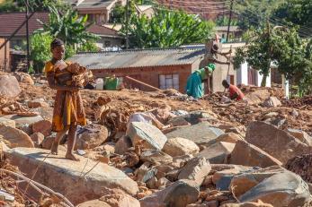 Woman in yellow dress walking among rubble