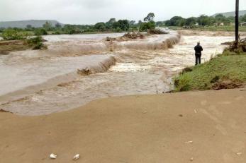 A person is pictured surveying the impact of a flooded river