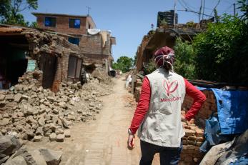 Mercy corps employee looking at homes impacted by the earthquake