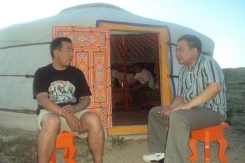 Two men sitting outside a ger on orange stools