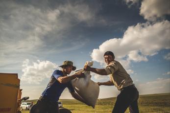 One man handing off a heavy bag to another