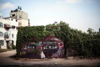 Mural depicting two human eyes on a wall under green vines