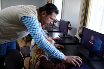 A mercy corps employee helping a child use a computer