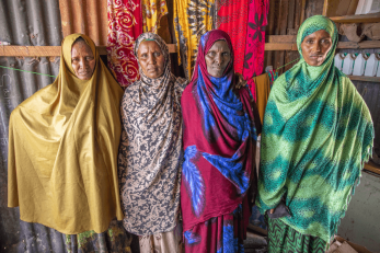 Four women in colorful clothing, standing together