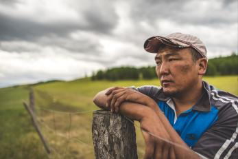 Enkh-erdene leaning on a fence post