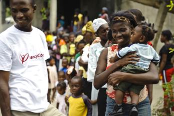 Man in mercy corps shirt and crowd of families with children