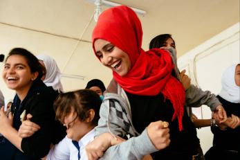 Zahra laughing and moving with a group of youth