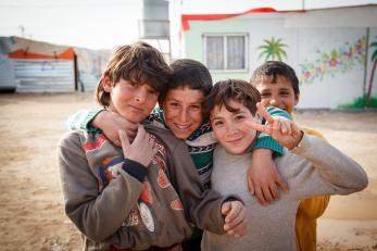 Four boys smiling together, one holding up a peace sign