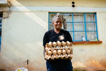 Lucy carrying a stack of eggs in cardboard containers