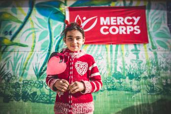 Girl in red sweater in front of mercy corps sign