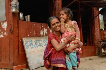 Harikala holding a young girl outside the shop