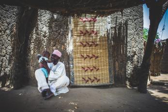 Alhaj holds his young son outside their home