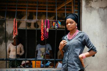 Woman standing next to necklaces for sale